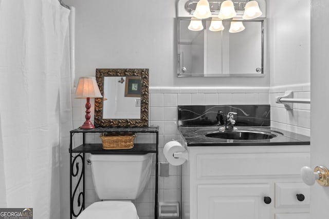 bathroom featuring tile walls, vanity, and toilet