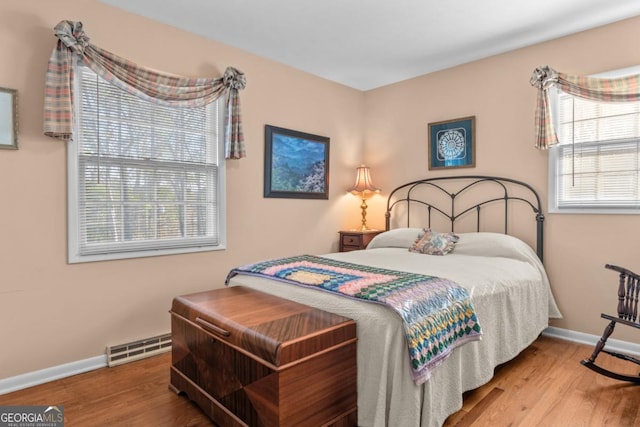 bedroom featuring a baseboard heating unit and hardwood / wood-style flooring