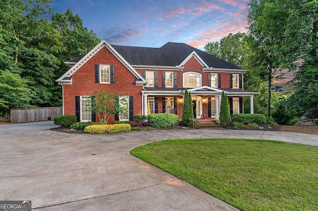 view of front of home featuring driveway, fence, and brick siding