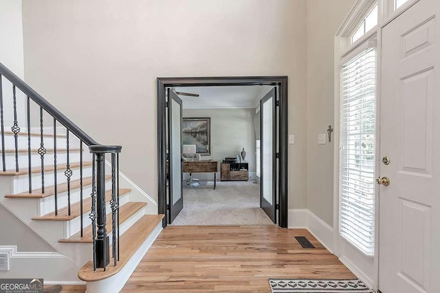 entrance foyer with baseboards, stairs, visible vents, and light wood-style flooring