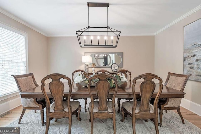 dining room with crown molding, a healthy amount of sunlight, light hardwood / wood-style flooring, and a notable chandelier