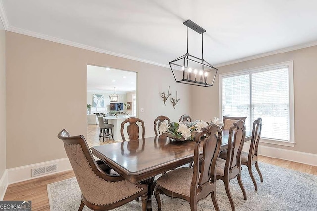 dining room featuring ornamental molding, a chandelier, and light wood-type flooring