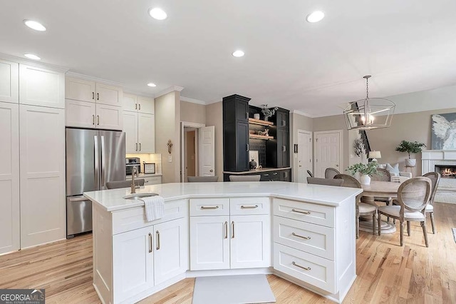 kitchen with a center island with sink, stainless steel fridge, pendant lighting, light hardwood / wood-style floors, and white cabinets