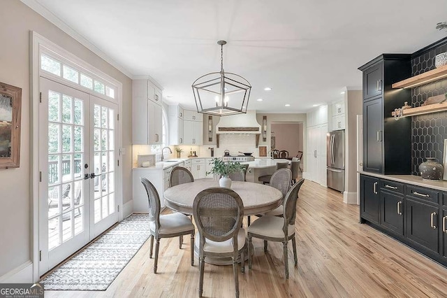 dining room featuring sink, crown molding, light hardwood / wood-style flooring, and french doors