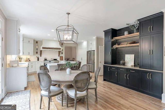 dining space with sink, a notable chandelier, and light hardwood / wood-style flooring