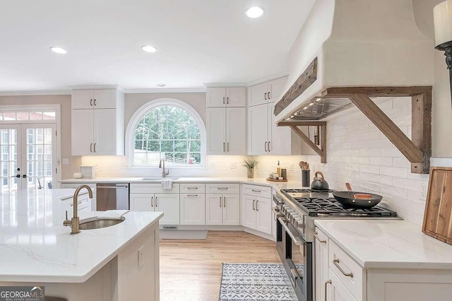 kitchen featuring sink, appliances with stainless steel finishes, backsplash, light stone countertops, and white cabinets