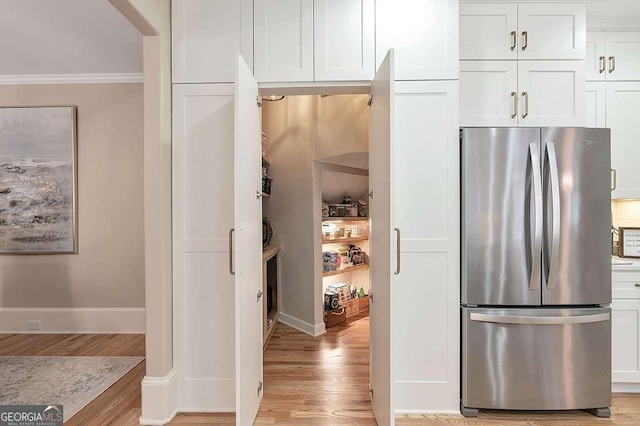 kitchen featuring crown molding, stainless steel fridge, light hardwood / wood-style flooring, and white cabinets