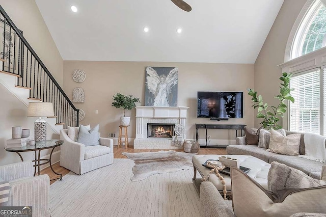 living room with high vaulted ceiling, a fireplace, and light hardwood / wood-style floors