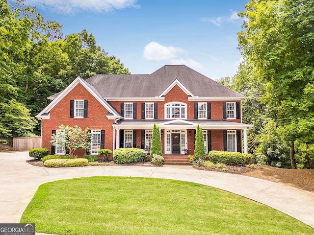 view of front of home featuring driveway, brick siding, a front yard, and fence