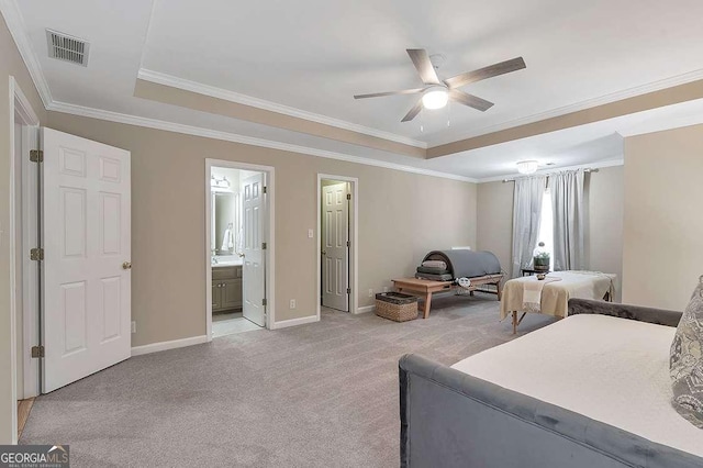 bedroom with connected bathroom, ornamental molding, ceiling fan, a tray ceiling, and light carpet