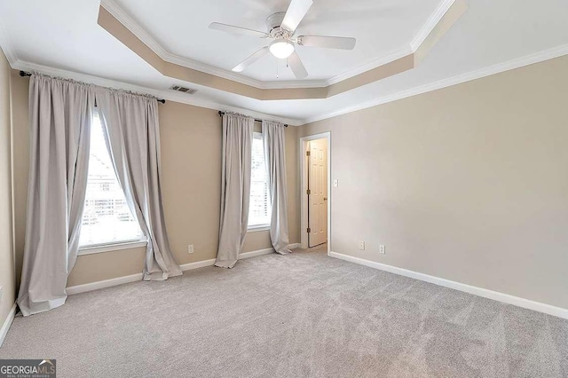 carpeted empty room with a wealth of natural light, ornamental molding, a raised ceiling, and ceiling fan