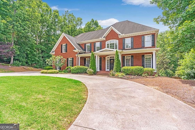 view of front of home with driveway, a front lawn, a porch, and brick siding