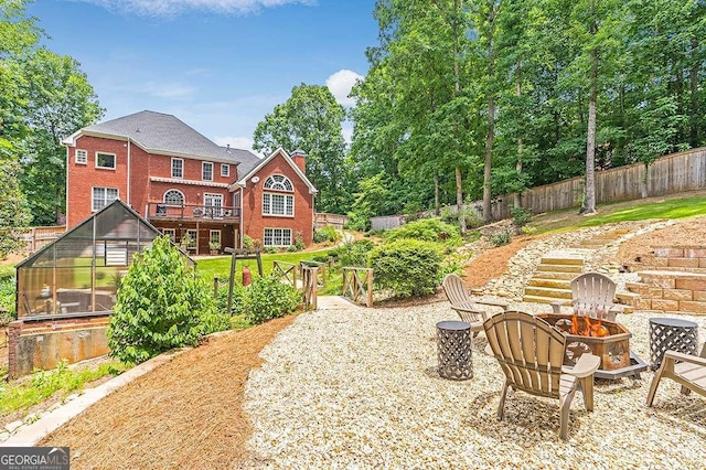 back of house featuring a fenced backyard, a fire pit, brick siding, an outdoor structure, and an exterior structure