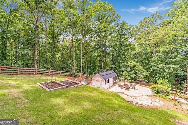 view of yard featuring a garden, a fenced backyard, and an outdoor structure