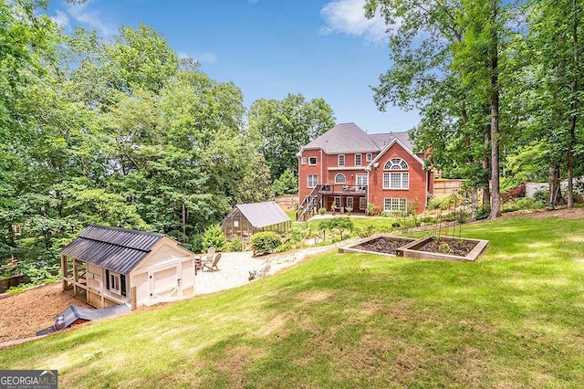 back of property featuring a yard, a garden, brick siding, and an outdoor structure