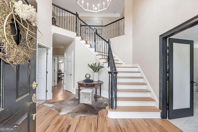 foyer featuring hardwood / wood-style flooring, ornamental molding, a chandelier, and a high ceiling