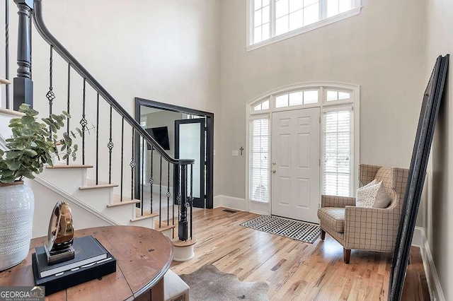 entrance foyer with a towering ceiling and light wood-type flooring