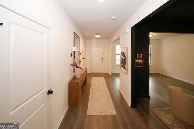 hallway featuring dark wood-style flooring and baseboards