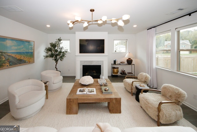 living area featuring a premium fireplace, a chandelier, wood finished floors, and recessed lighting