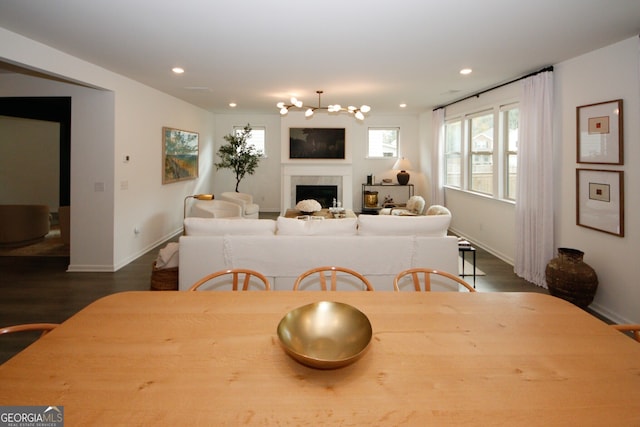 dining space with dark wood-style flooring, a fireplace, recessed lighting, an inviting chandelier, and baseboards