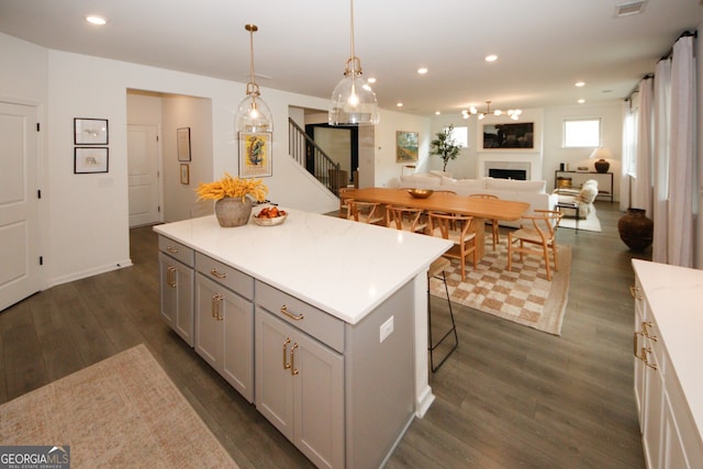 kitchen featuring open floor plan, hanging light fixtures, gray cabinets, light countertops, and a fireplace