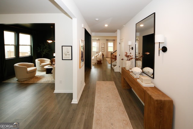 corridor with stairs, dark wood-style flooring, and a wealth of natural light