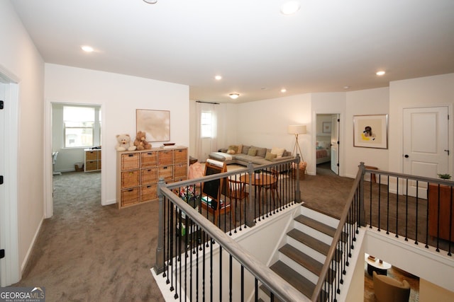 interior space featuring recessed lighting, baseboards, dark colored carpet, and an upstairs landing