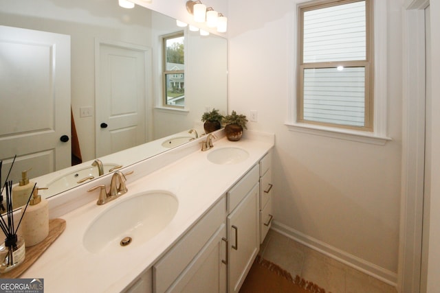 full bath featuring double vanity, a sink, and baseboards