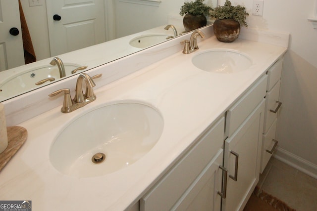 full bath featuring double vanity, a sink, and baseboards