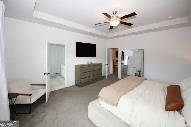 bedroom featuring light carpet, a tray ceiling, a ceiling fan, and baseboards