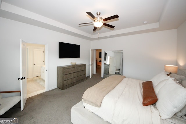 bedroom with ensuite bath, a raised ceiling, a ceiling fan, and light colored carpet