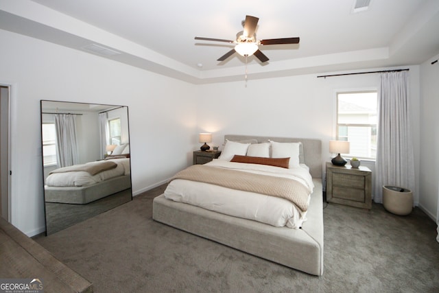 carpeted bedroom featuring baseboards, visible vents, and a raised ceiling