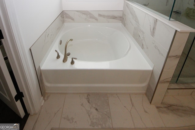 bathroom with marble finish floor and a bath