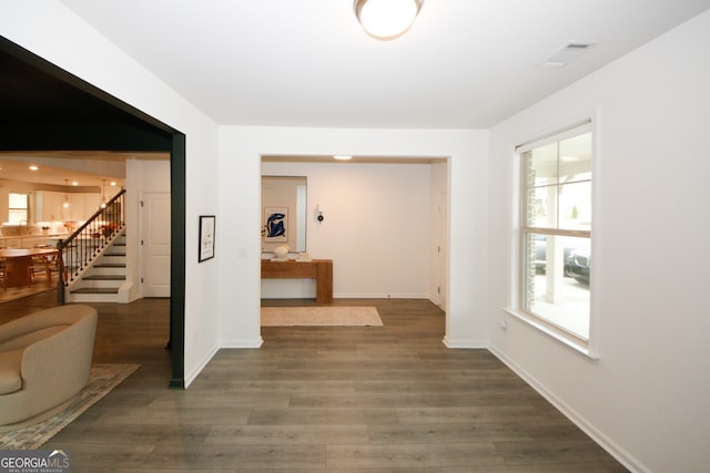 hall with visible vents, dark wood finished floors, stairway, and baseboards