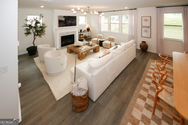 living room featuring recessed lighting, a fireplace with raised hearth, dark wood finished floors, and baseboards