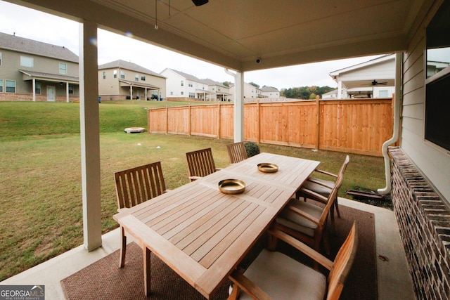 view of patio with a residential view, fence, outdoor dining area, and a ceiling fan