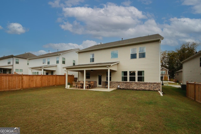 back of house featuring a patio area, a lawn, a fenced backyard, and brick siding