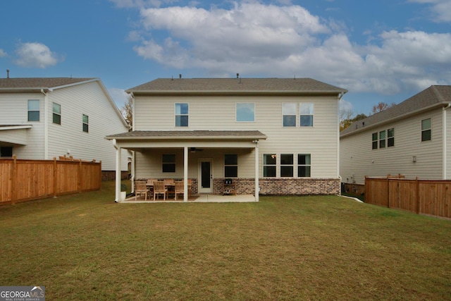 back of house with a fenced backyard, a patio, brick siding, and a lawn