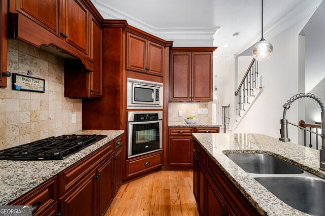 kitchen with light stone countertops, appliances with stainless steel finishes, sink, and pendant lighting