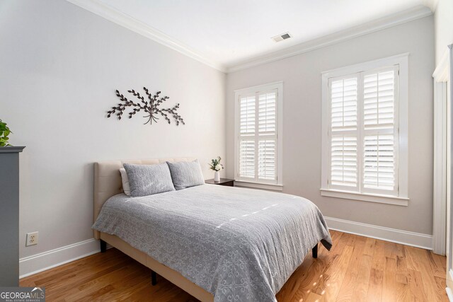 bedroom with multiple windows, ornamental molding, and hardwood / wood-style floors