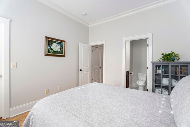 bedroom featuring hardwood / wood-style flooring, ornamental molding, and ensuite bathroom