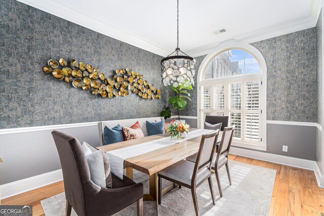 dining space featuring hardwood / wood-style flooring, ornamental molding, and a wealth of natural light