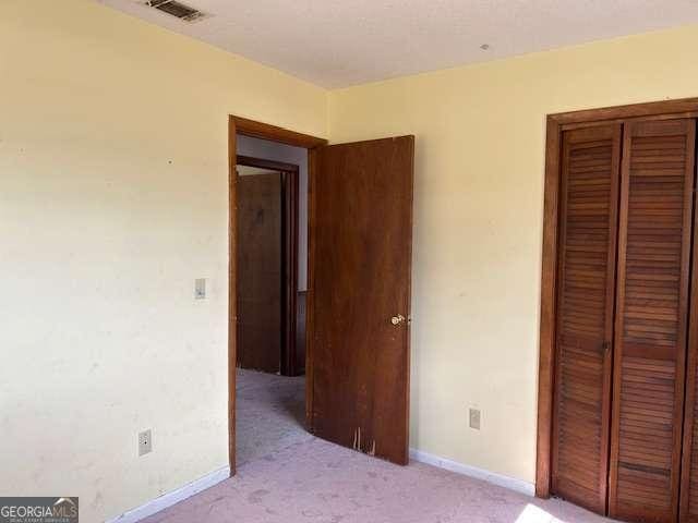 unfurnished bedroom featuring light carpet and a closet