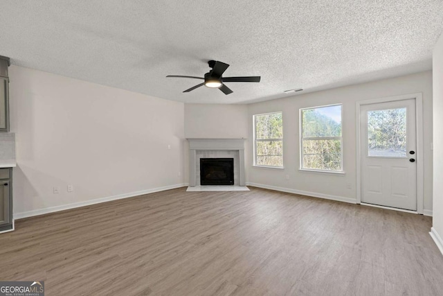 unfurnished living room with ceiling fan, a textured ceiling, and light hardwood / wood-style floors