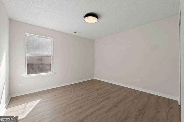 spare room featuring hardwood / wood-style flooring and a textured ceiling