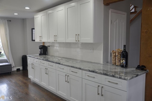 kitchen featuring dark hardwood / wood-style flooring, backsplash, white cabinets, and light stone counters