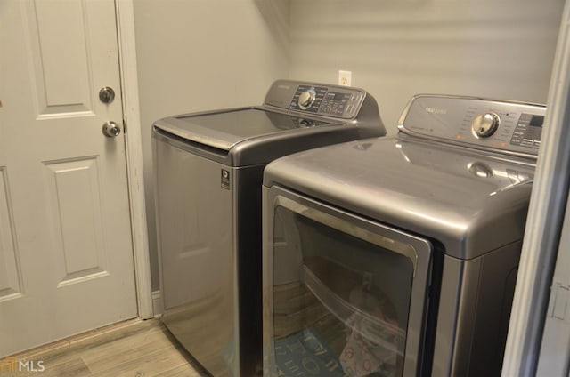 washroom with separate washer and dryer and light hardwood / wood-style flooring