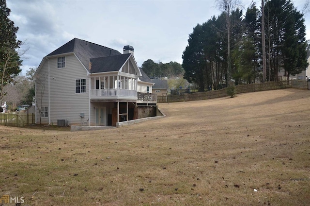 rear view of property featuring central AC, a wooden deck, and a lawn