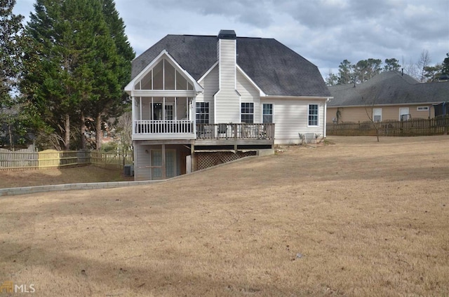 rear view of property featuring a wooden deck, a sunroom, cooling unit, and a lawn