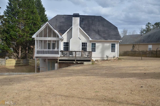 rear view of house with a wooden deck, a yard, and a sunroom